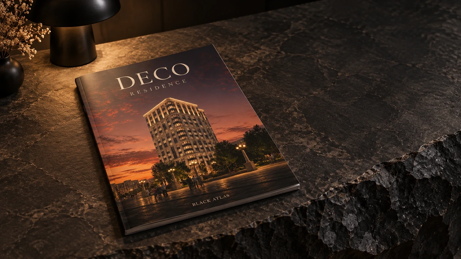Каталог Deco Residence с вечерней фотографией дома на обложке лежит на каменной стойке рядом с лампой