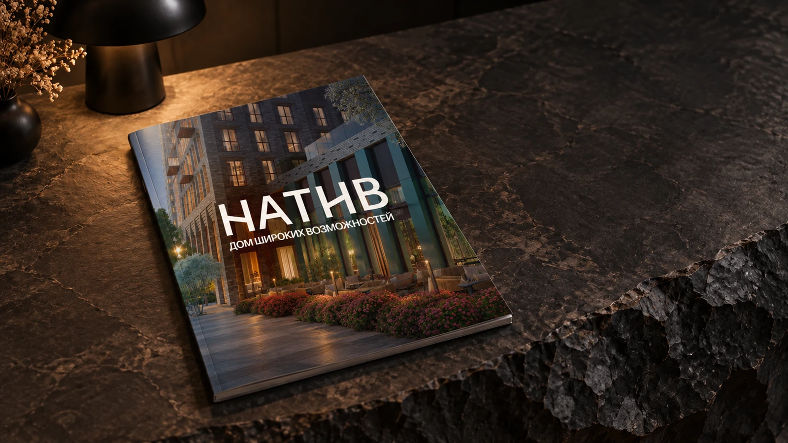 Каталог Натив с вечерней фотографией дома на обложке лежит на каменной стойке рядом с лампой